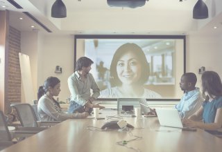 Men and women enjoying high QoS for video conferencing.