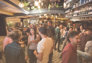 A crowd of patrons waits for tables in a restaurant that uses SMS restaurant communications