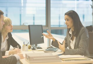A credit union employee uses new communications solutions to assist two members with a loan