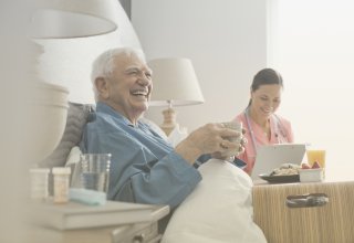 An elderly patient's caregiver uses patient care technology to communicate with a physician