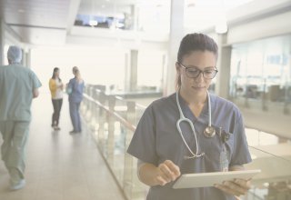 A healthcare employee using tech solutions that drive healthcare cost management on a tablet