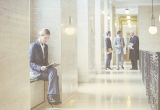 A lawyer beating law firm competition by communicating with clients on a tablet while in courthouse