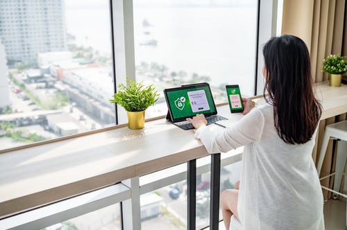 A woman working near window verifying login with 2FA on devices. Concept of passwordless authentication.