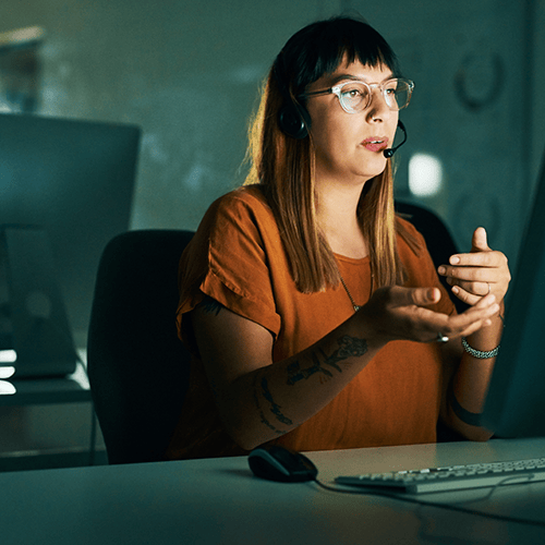 image of woman on headset in front of computer