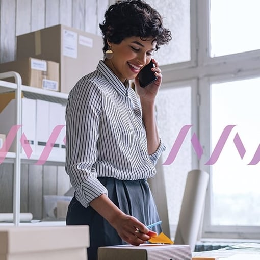 Photo of a smiling woman talking on the phone in an office setting.