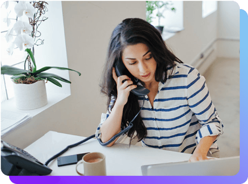 Calls ringing on multiple extensions Woman on desk phone looking at her laptop and cell phones which ring at the same time