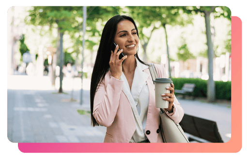 Young business woman smiling while on phone while holding a cup of coffee outside