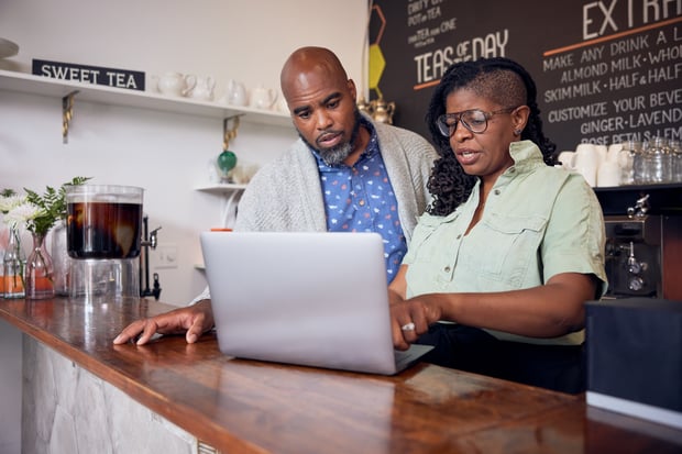 Black tea shop owners work on a laptop as they run their business
