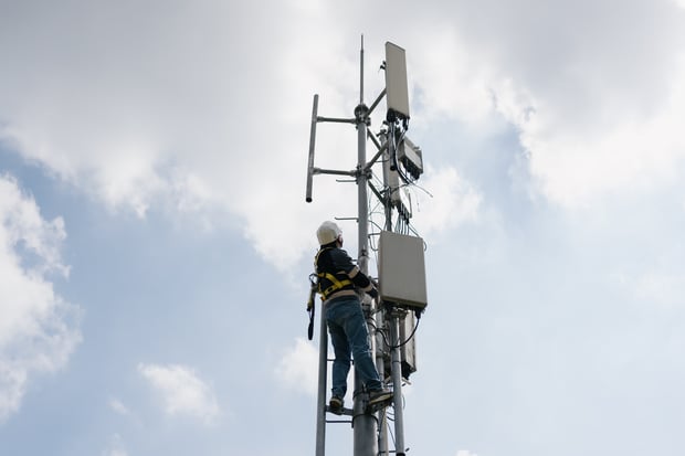 An aerial view of a modern urban city skyline with enterprise 5G wireless network connectivity towers and infrastructure