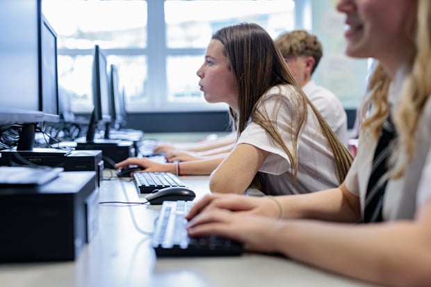 STEM students working together in a modern high school computer lab, a similar scene to the hands-on classes presented by Vonage and Girls Who Code