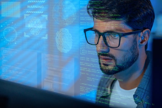 A computer user analyzing code and a security fingerprint on a screen. What's Keeping Your Agents in Line blog article.