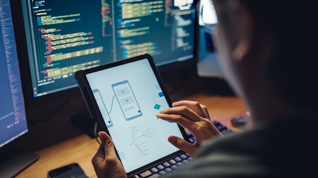A software developer examines UX flowcharts and design wireframes for a mobile app, a nod to the Network API market potential.