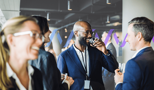 Smiling entrepreneur enjoying a beverage while chatting with colleagues at a networking event