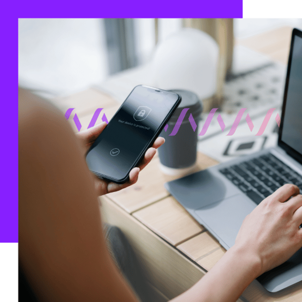 Photo of woman, POV over her shoulder from behind. On the desk in front of her is an open laptop and she is holding her cell phone.. In the background, a series of small purple  waves run across the frame, representing communication.