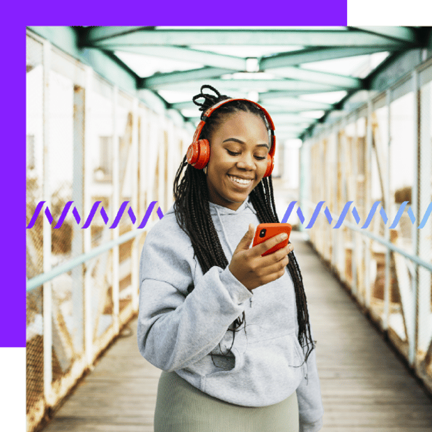 Photo of a smiling casually dressed woman wearing headphones. She is holding her cell phone and appears to be reading a text message. In the background, a series of small wave forms runs across the frame.