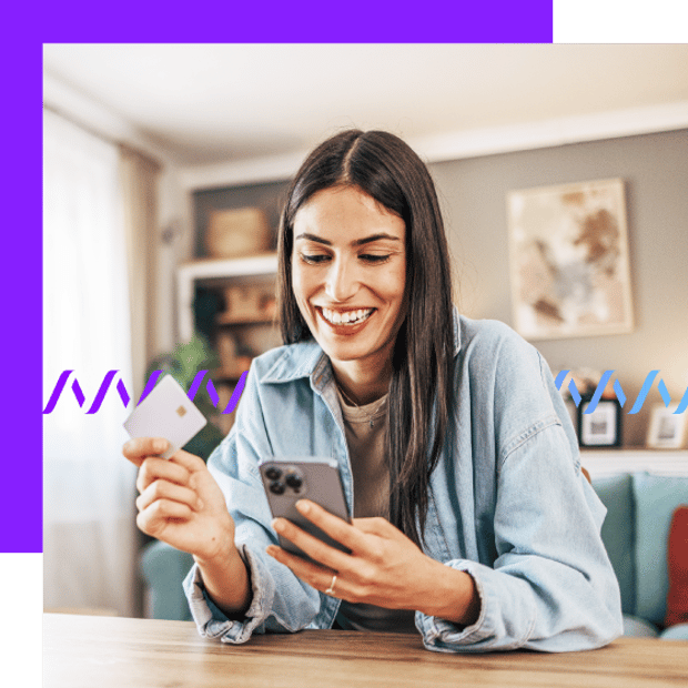 Photo of a smiling woman at home, holding her cell phone in one hand and her credit card in the other. She is looking at the screen on her phone. In the background, a series of small gradient purple waveforms runs across the frame, representing e-commerce activity.