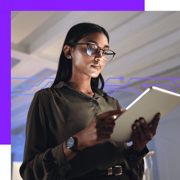 Photo of a dramatically lit woman in an office looking at her tablet. In the background, a series of small purple symbols run across the frame, representing digital connections.