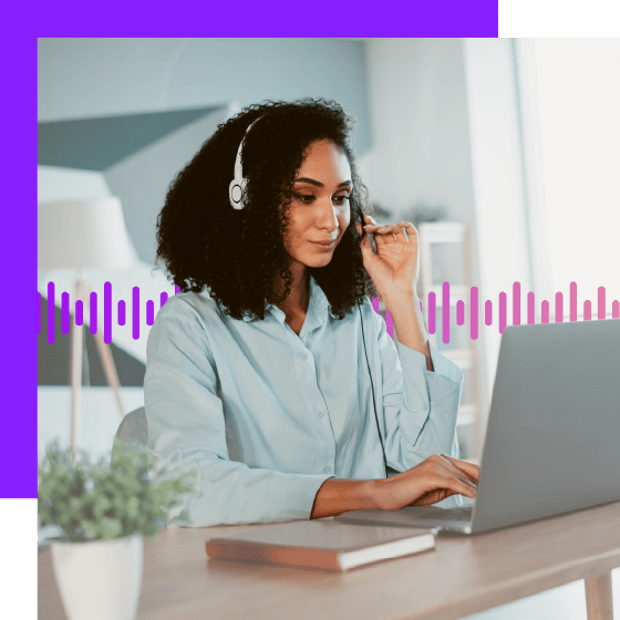 Photo of a woman working on her laptop and wearing a headset.