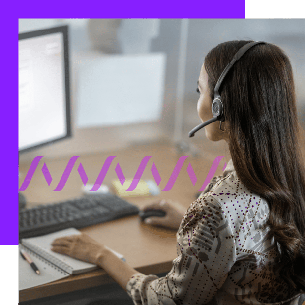 Photo of a female contact center agent wearing a headset and working at her computer.