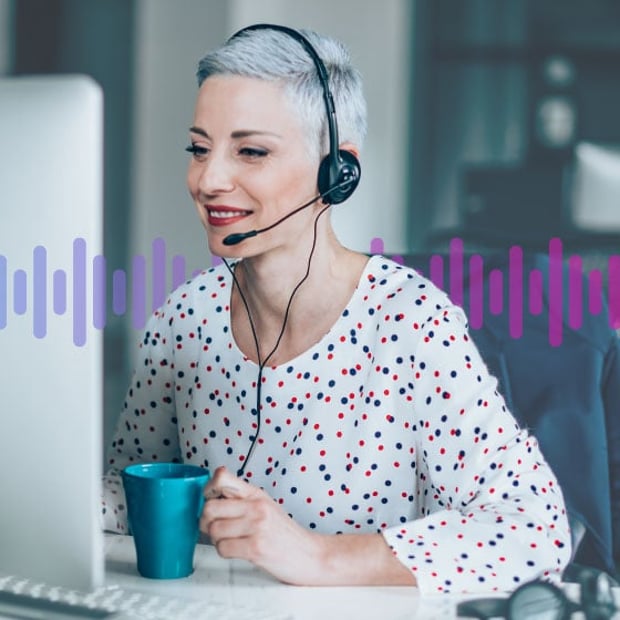 CC as Business Hub Blog Header Photo of smiling female contact center agent looking at her computer screen as talks to a customer through her headset.