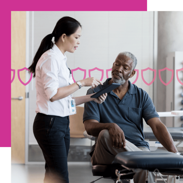 Photo of a doctor in an exam room holding her tablet and discussing care with a patient. In the background, a series of pink shield-shape icons runs across the frame.