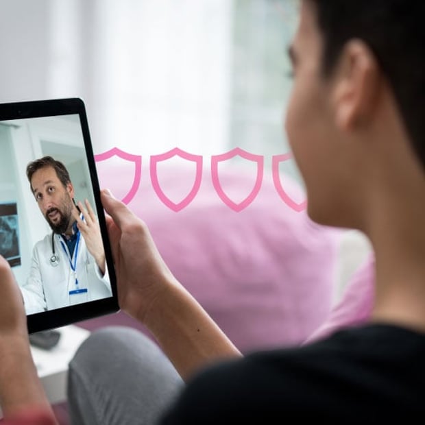 Photo of a female patient at home looking at her tablet. On the screen is a doctor discussing the patient's health situation. 