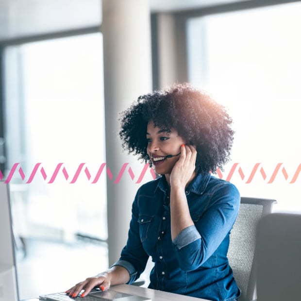 UC SEO BPO Call Center Blog Header Photo of a smiling woman in an office talking into her headset and looking at her computer. In the background, a series of small wave-like icos run across the frame, representing communication.