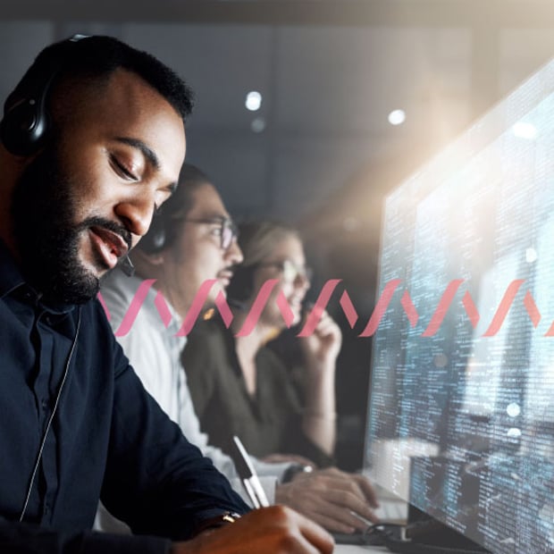SEO Contact Center Technology Blog Header Photo of a row of contact center agents, shot from the side, as they handle calls from customers, take notes, and look at their computer monitors. A series of small pink waves runs across the frame.