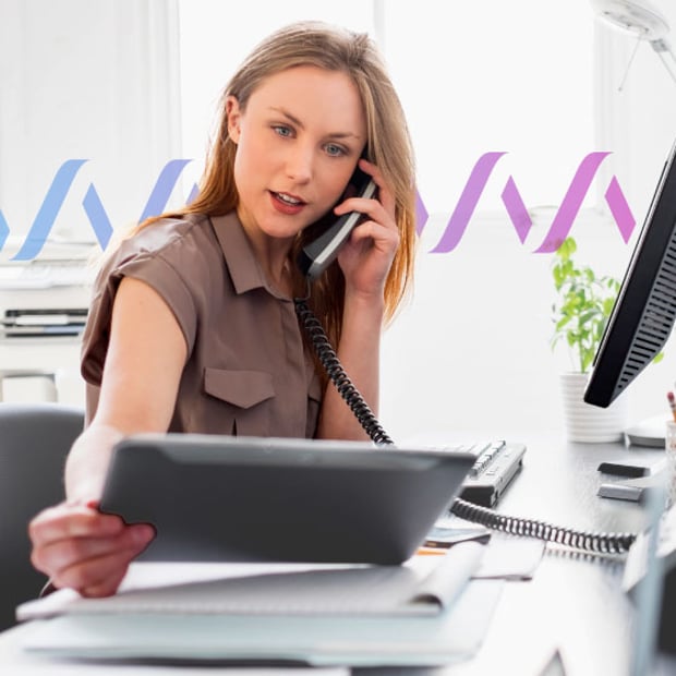 UC Analytics Blog Header Photo of a woman looking at some documents while talking on her business phone.