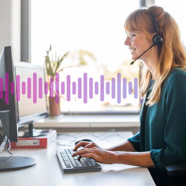 UC SEO First Call Resolution Blog Header Photo of a smiling female call center agent sitting at her computer and talking to a customer through her headset. In the backgound, a small series of purple vertical lines run across the frame, representing communication.