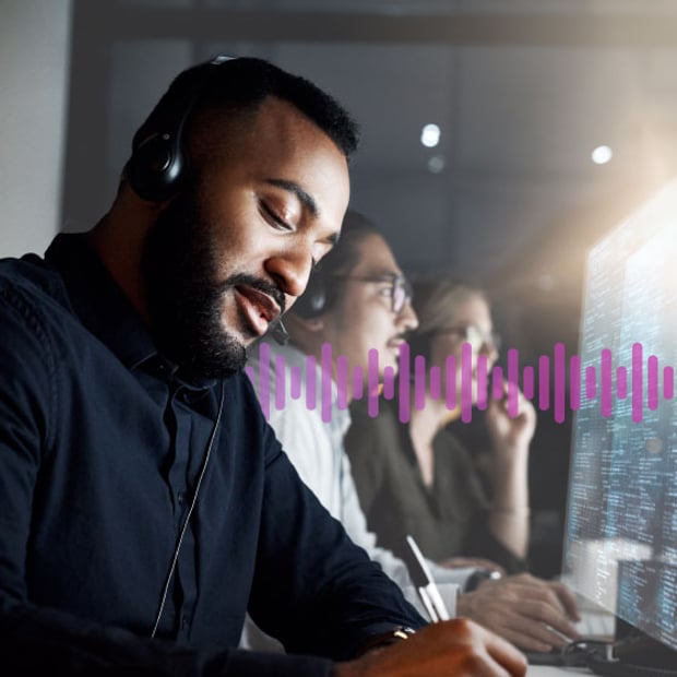 UC SEO Call Center Monitoring Blog Header Photo of a row of call center agents dealing with customers on their phones while looking at data on the computer monitors. In the background, a series of small purple vertical lines runs across the frame.