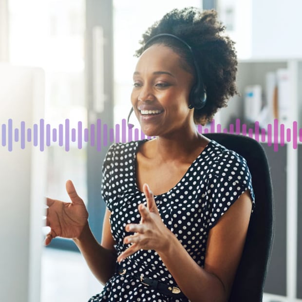UC SEO How to Transfer Call Blog Header Photo of a smiling agent in an office gesturing with her hands as she talks to a customer on her phone headset. In the background, a series of small purple vertical lines runs across the frame.