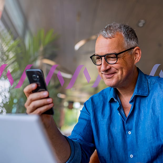 Photo of a smiling man looking at something on his cell phone screen