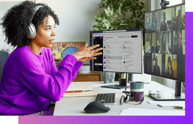 A person at a desktop computer setup on a Microsoft Teams video call with Teams open in the background.
