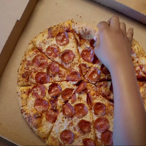 Vonage Does That Pizza Video Thumbnail Hand reaching into pizza box grabbing a slice