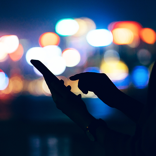backlit image of a hand holding a phone
