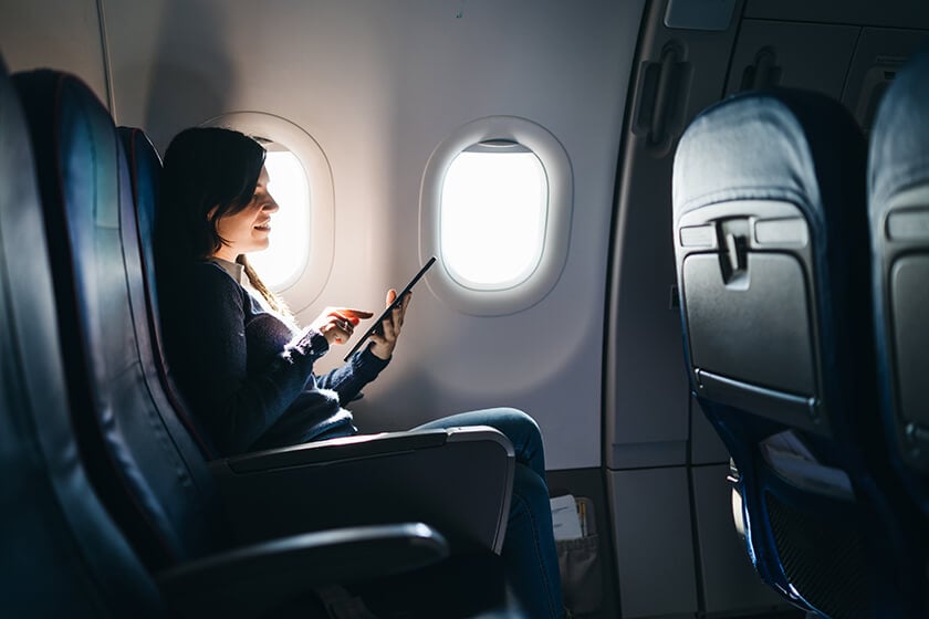 woman on airplane looking at tablet
