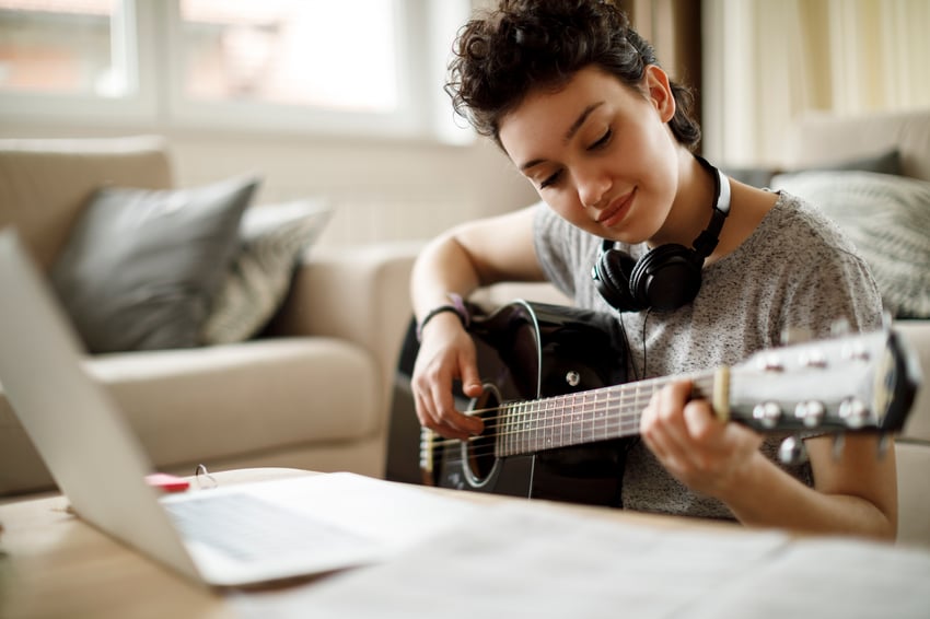 Smiling girl playing a guitar at home