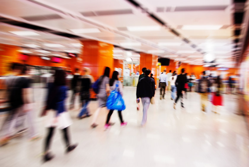 Colorful photo of a crowd of shoppers in a mall. The photo is blurred to show movement.