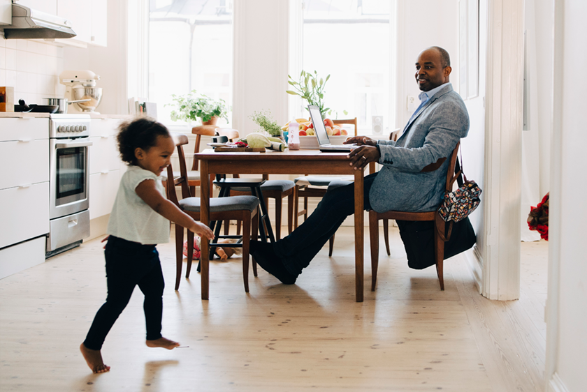 Remote work man child man working from kitchen smiling at child running nearby