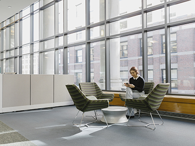 Hispanic Businesswoman Using Mobile Phone Alone In Office Lobby Person using a Slack integration on their smartphone and laptop