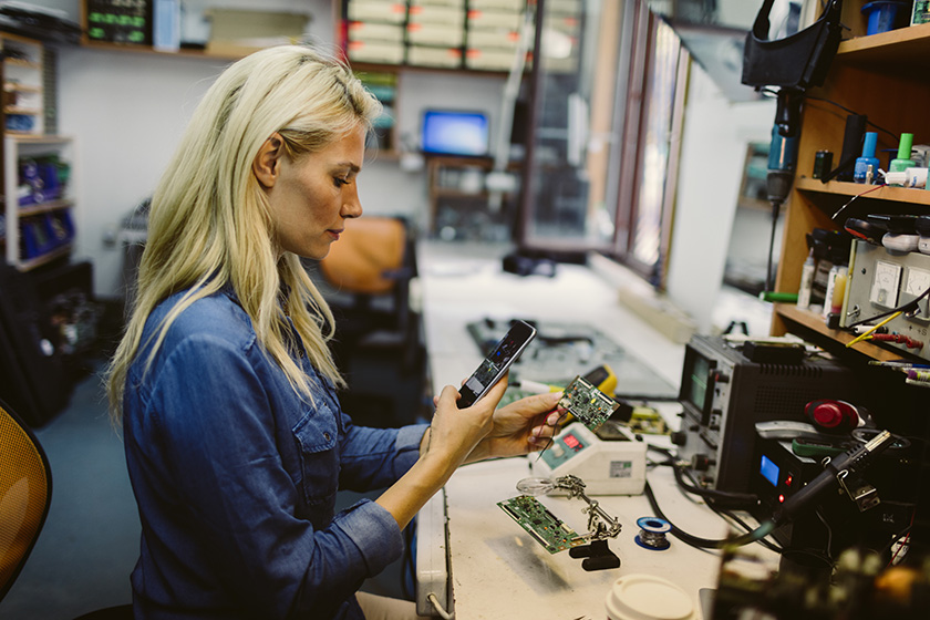 Woman looking at phone while fixing equipment